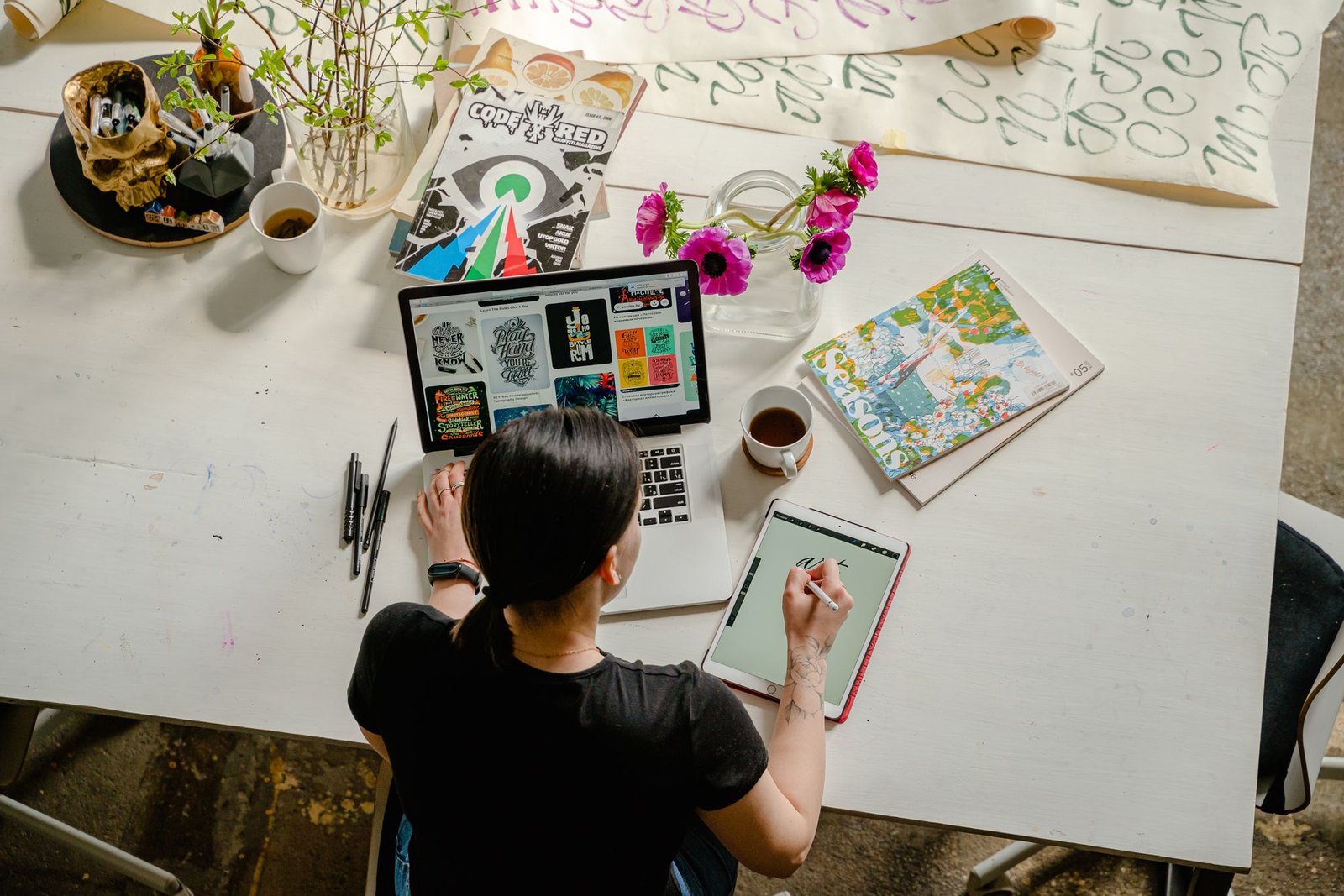 An operator planning visual content at a desk with a laptop and printed material