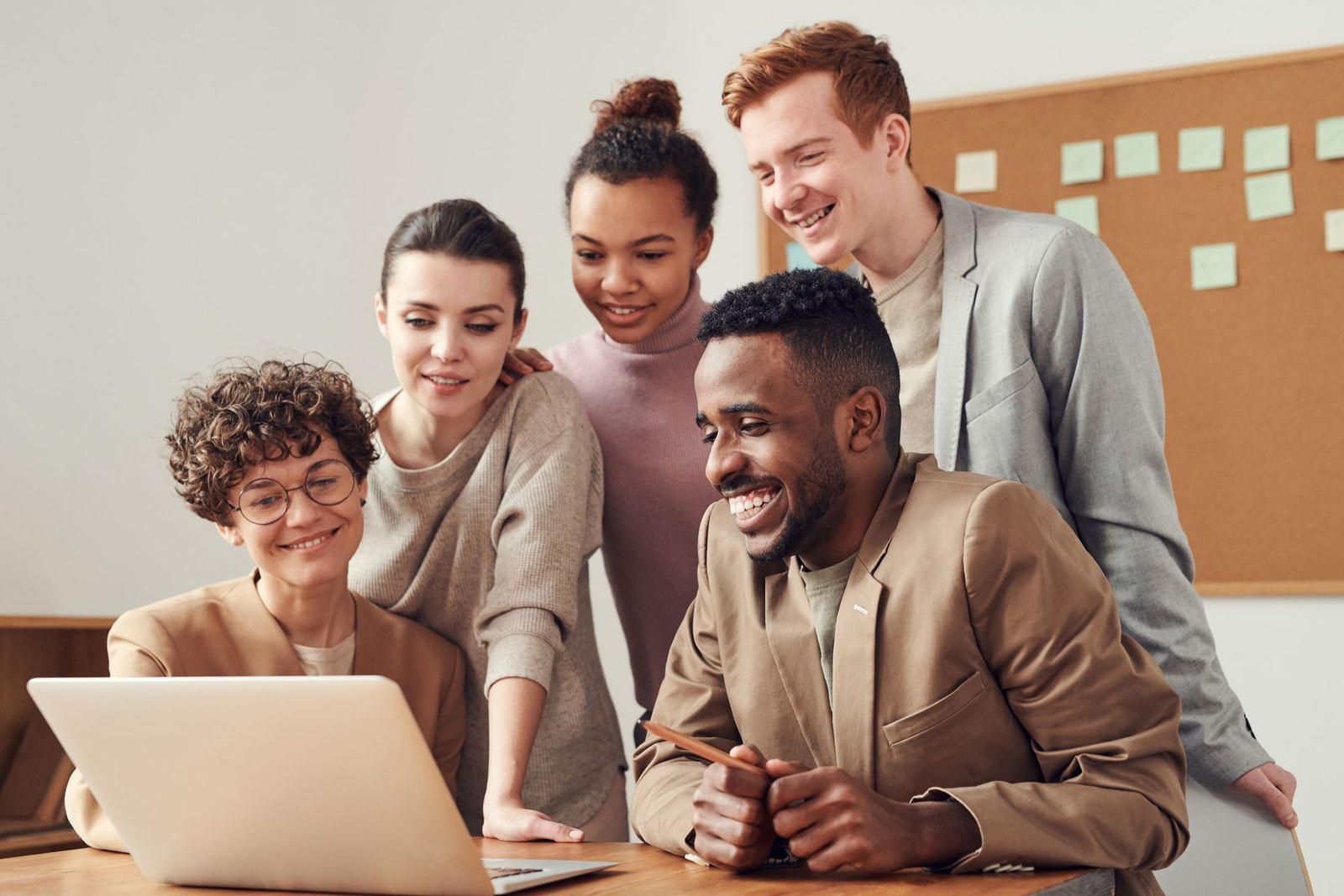 A team reviewing work together around a laptop